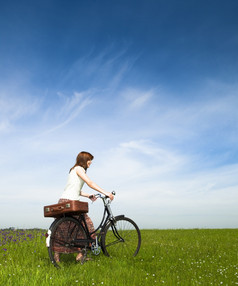 快乐年轻的女人绿色草地与古董自行车