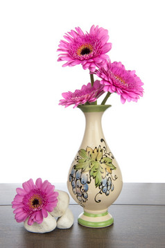 粉红色的非洲菊装饰花瓶与桩白色岩石黑暗棕色（的）木架子上
