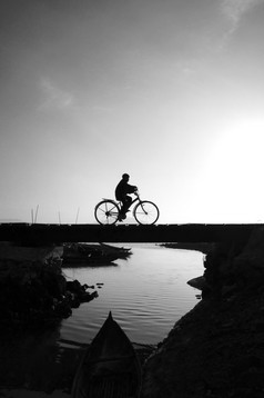 轮廓孤独的年轻的男孩骑自行车小桥交叉的河早....骑自行车休闲这使伤心平静场景农村