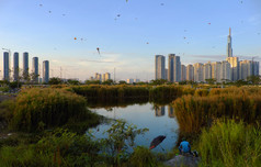 令人惊异的景观谁警察局城市越南许多风筝飞行日落天空高上升建筑反映水已经花和男人。坐为钓鱼前景使美妙的场景