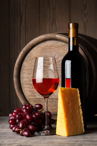 瓶而且玻璃红色的酒与奶酪而且葡萄的背景的桶瓶而且玻璃红色的酒与奶酪而且葡萄