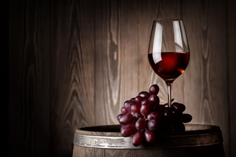 玻璃红色的酒与葡萄木桶的木墙玻璃红色的酒与葡萄木桶