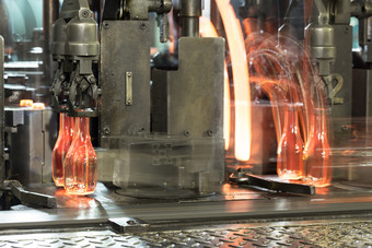 输送机与热玻璃瓶热红色的瓶移动沿着的输送机的玻璃工厂爽肤水输送机与热玻璃瓶