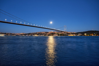 横跨博斯普鲁斯海峡桥的背景的晚上海岸下的明亮的月亮伊斯坦布尔火鸡晚上景观横跨博斯普鲁斯海峡桥背景晚上海岸下明亮的月亮