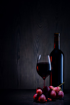 红色的酒玻璃和瓶和群葡萄木表格红色的酒玻璃和瓶和群葡萄木表格