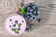浆果奶昔酸奶玻璃和蓝莓碗木表格薄荷玻璃和的表格的概念排毒视图从以上浆果奶昔酸奶玻璃和蓝莓碗