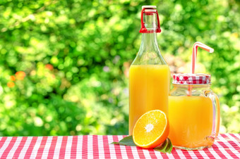 玻璃Jar和瓶与橙色汁一半橙色与叶子自然<strong>绿色背景</strong>玻璃Jar和瓶与橙色汁