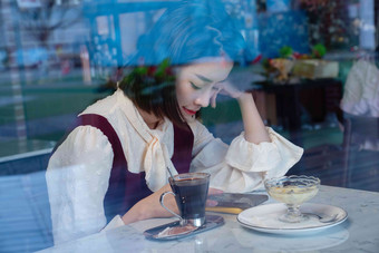咖啡馆内边喝咖啡边使用手机的青年女人