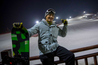 夜晚青年男人坐在滑<strong>雪</strong>场内的护栏上