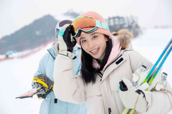 滑雪场上快乐的青年伴侣拿着雪具