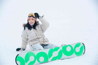 踩着单板坐在雪地上的青年女人