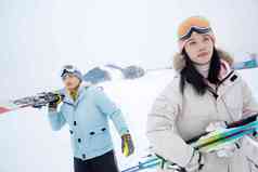 雪场上拿着滑雪板去滑雪的情侣