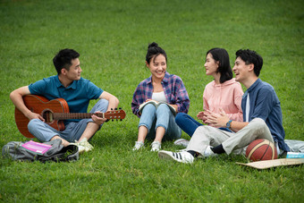 快乐的大学生在草地上弹吉他唱歌