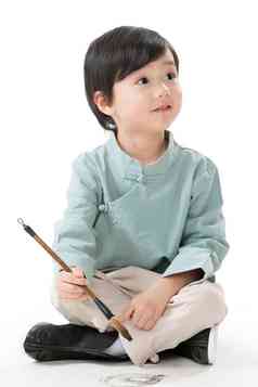 小男孩盘腿坐着拿毛笔写字