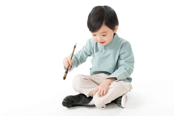 可爱的小男孩坐在地上用<strong>毛笔</strong>写字