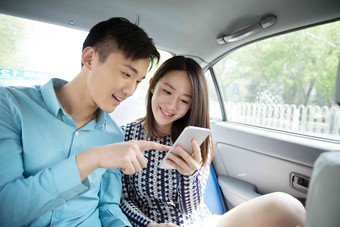 青年情侣在车内看手机