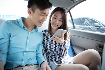 青年情侣在车内看手机