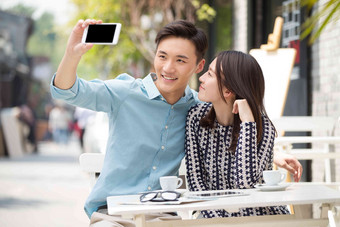 青年情侣坐在咖啡馆里用手机自拍