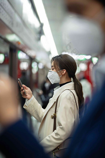 戴口罩的年轻女人在<strong>地铁</strong>里看手机