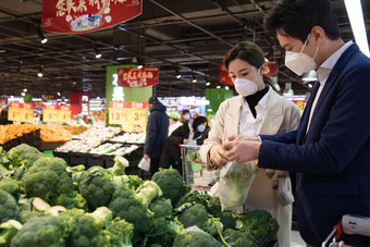 青年夫妇戴口罩在超市购买青菜