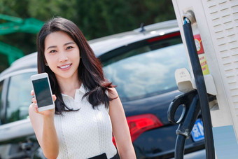 青年女人使用手机自助充电汽车