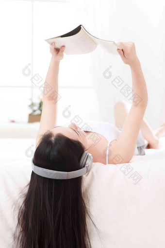 青年女人在卧室的床上听音乐