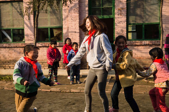 乡村教师和小学生在学校里做游戏