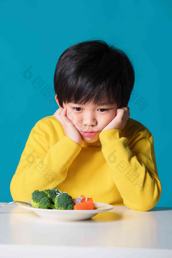 盯着蔬菜发愁的小男孩