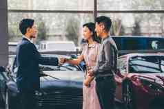 汽车销售人员和青年夫妇握手