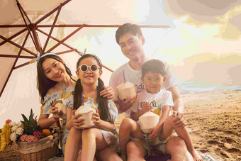 幸福的四口之家坐在沙滩上喝<strong>椰汁</strong>