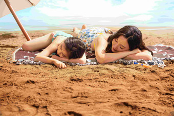幸福母女趴在沙滩上睡觉