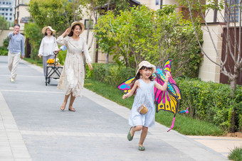 拿着<strong>风筝</strong>的小女孩和家人在户外玩耍