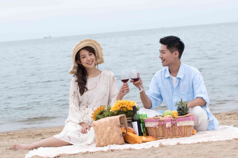 浪漫的青年夫妇坐在沙滩上喝<strong>红酒</strong>