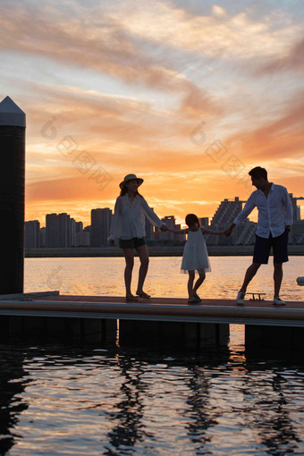 夕阳下一家三口在海边玩耍