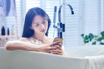 浴缸内使用手机的年轻女孩