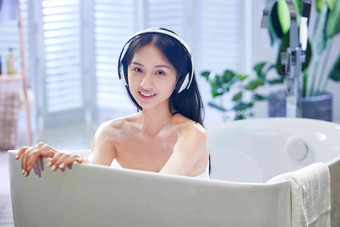 浴缸内听音乐的年轻女孩