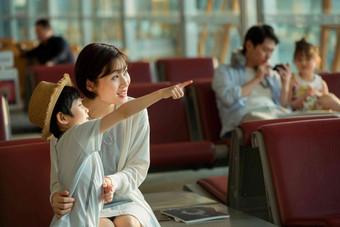 年轻妈妈和儿子坐在机场候机厅