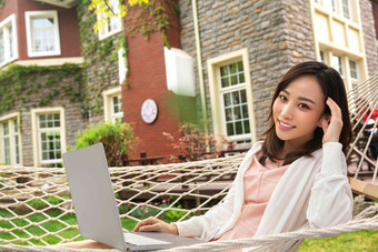 青年女人在院子里用笔记本电脑