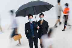 拿着雨伞的商务男女戴着口罩站在人群中