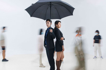 拿着雨伞的商务男女站在人群中