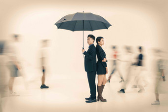 拿着雨伞的商务男女站在人群中