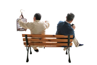 拿着鸟笼的老人和拿着手机的老人坐在长椅上