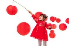 红灯笼旁提着灯笼玩耍的小女孩
