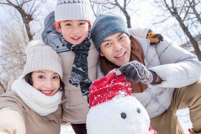 一家三口在雪地里堆雪人白昼高清拍摄