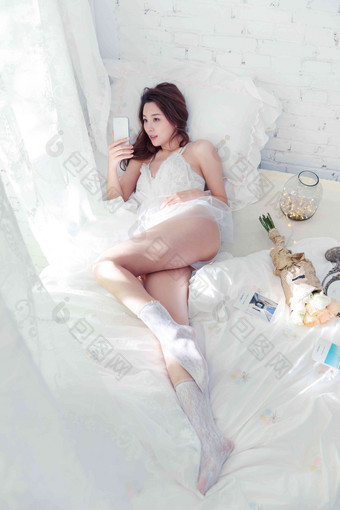 青年女人躺在床上用手机自拍