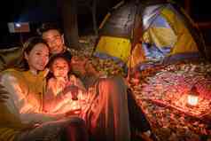 幸福的一家三口夜晚在野外露营