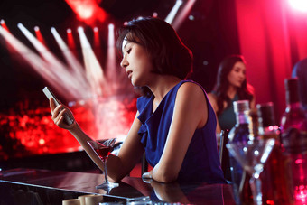 青年女人在酒吧看手机