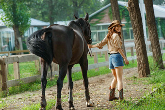 时尚自信的青年女人牵着马
