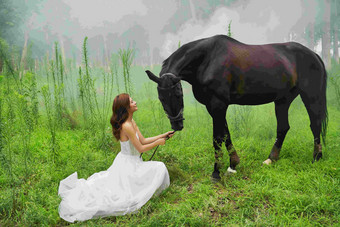 草地上穿婚纱的青年女人牵着马