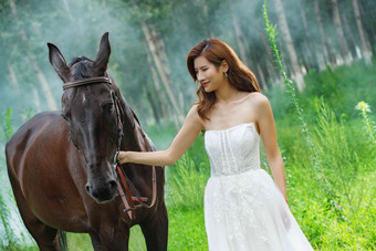 树林里漂亮的青年女人牵着马